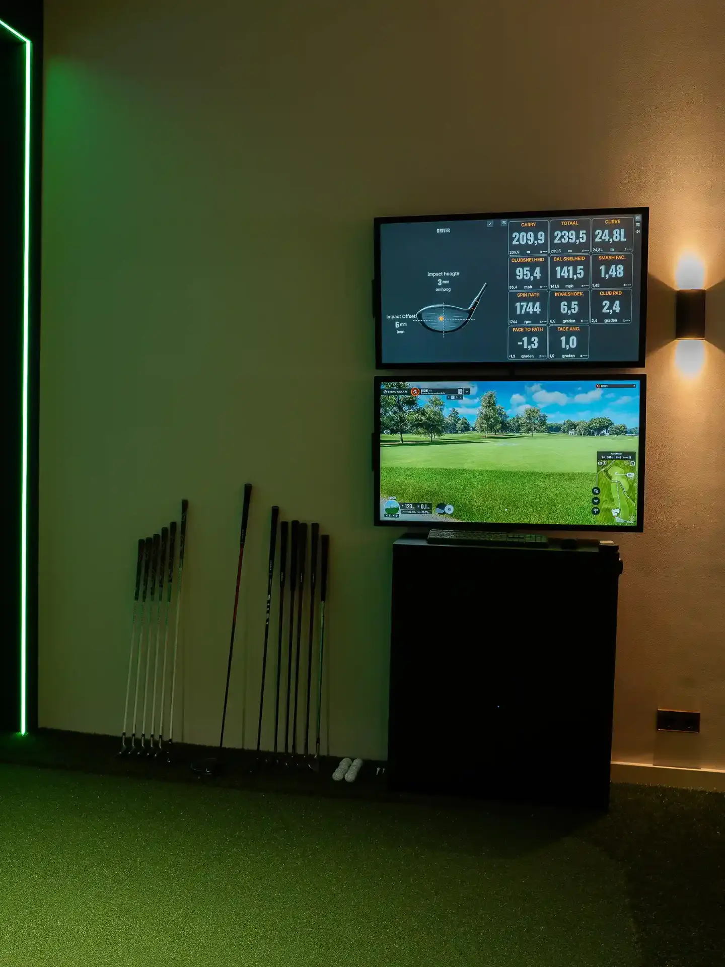 Golfclubs klaargezet naast de TrackMan-schermen in een bay