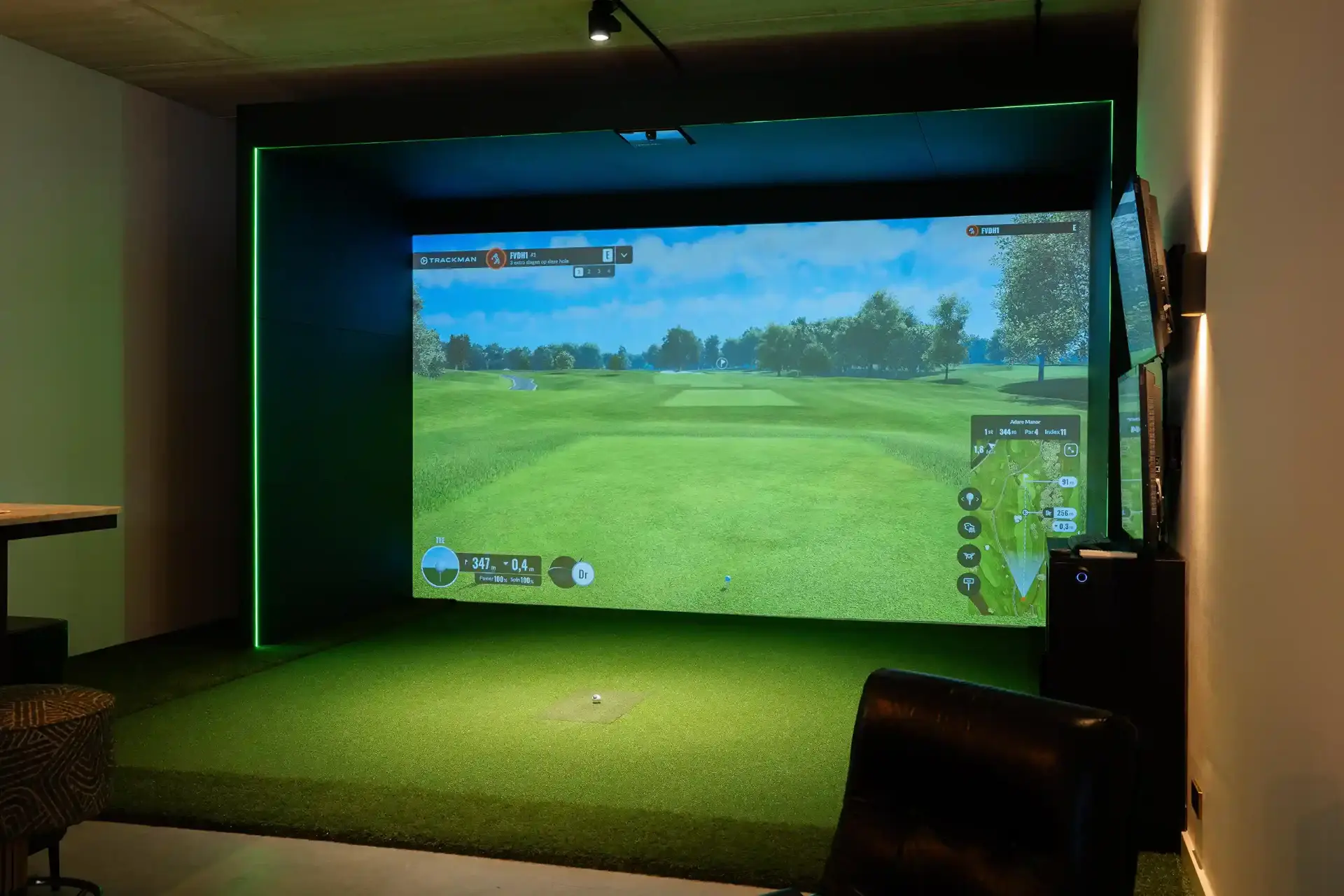 Golfsimulator met groot projectiescherm in een donker verlichte ruimte