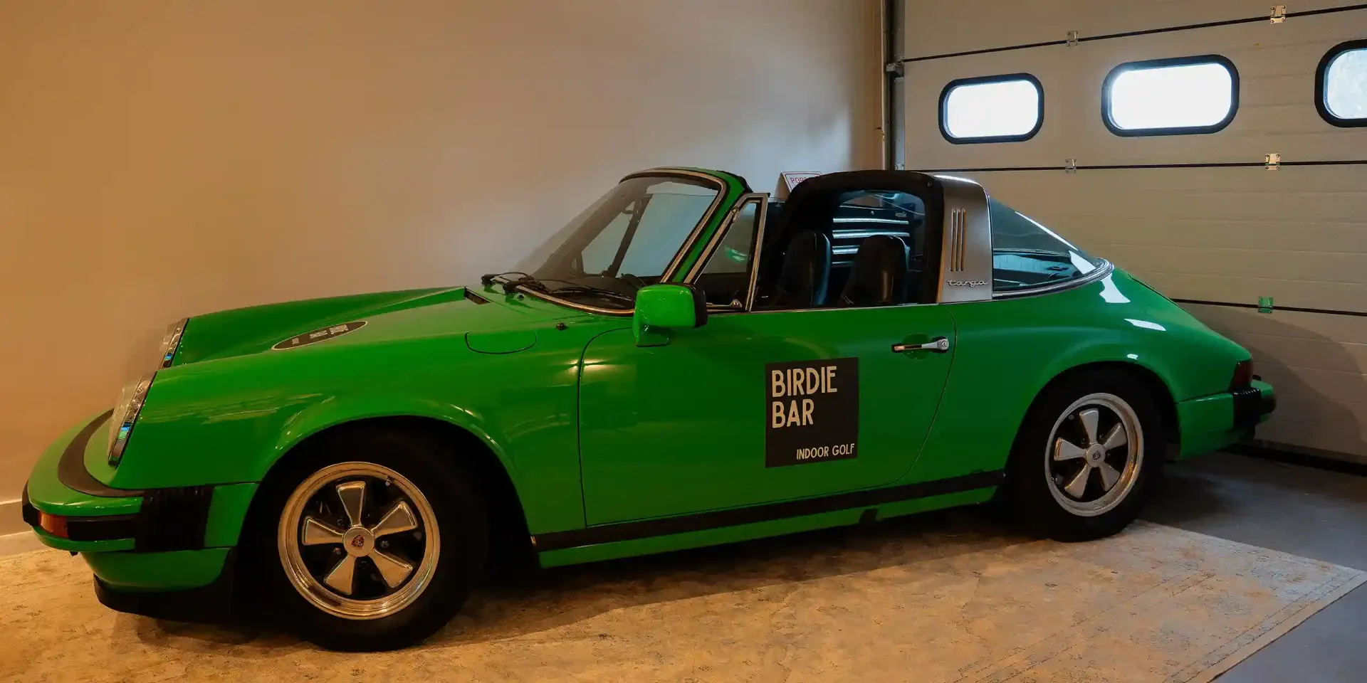 Spelers bij een indoor golfbay van Birdie Bar in gedempt avondlicht